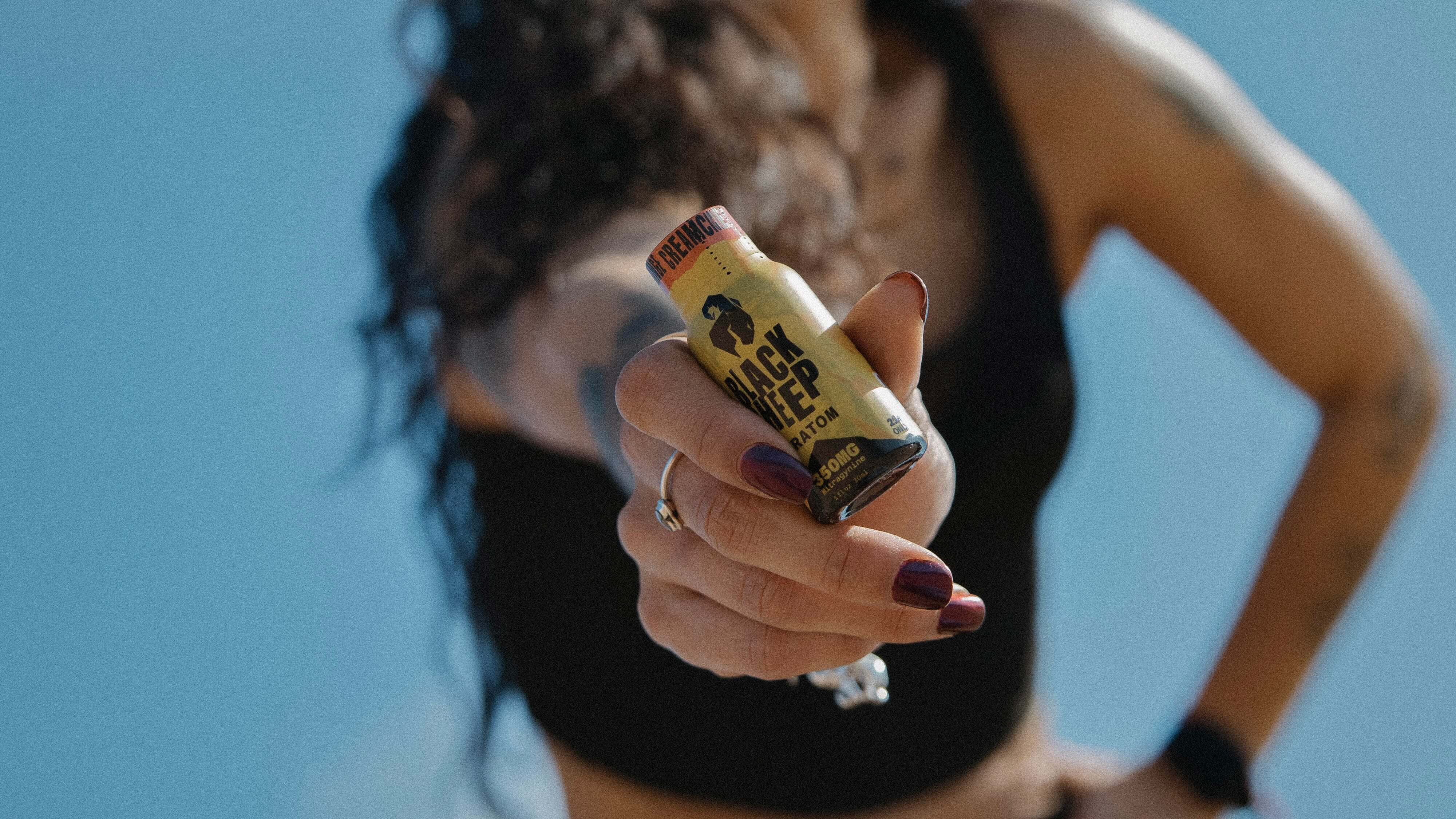 woman holding a black sheep kratom shot