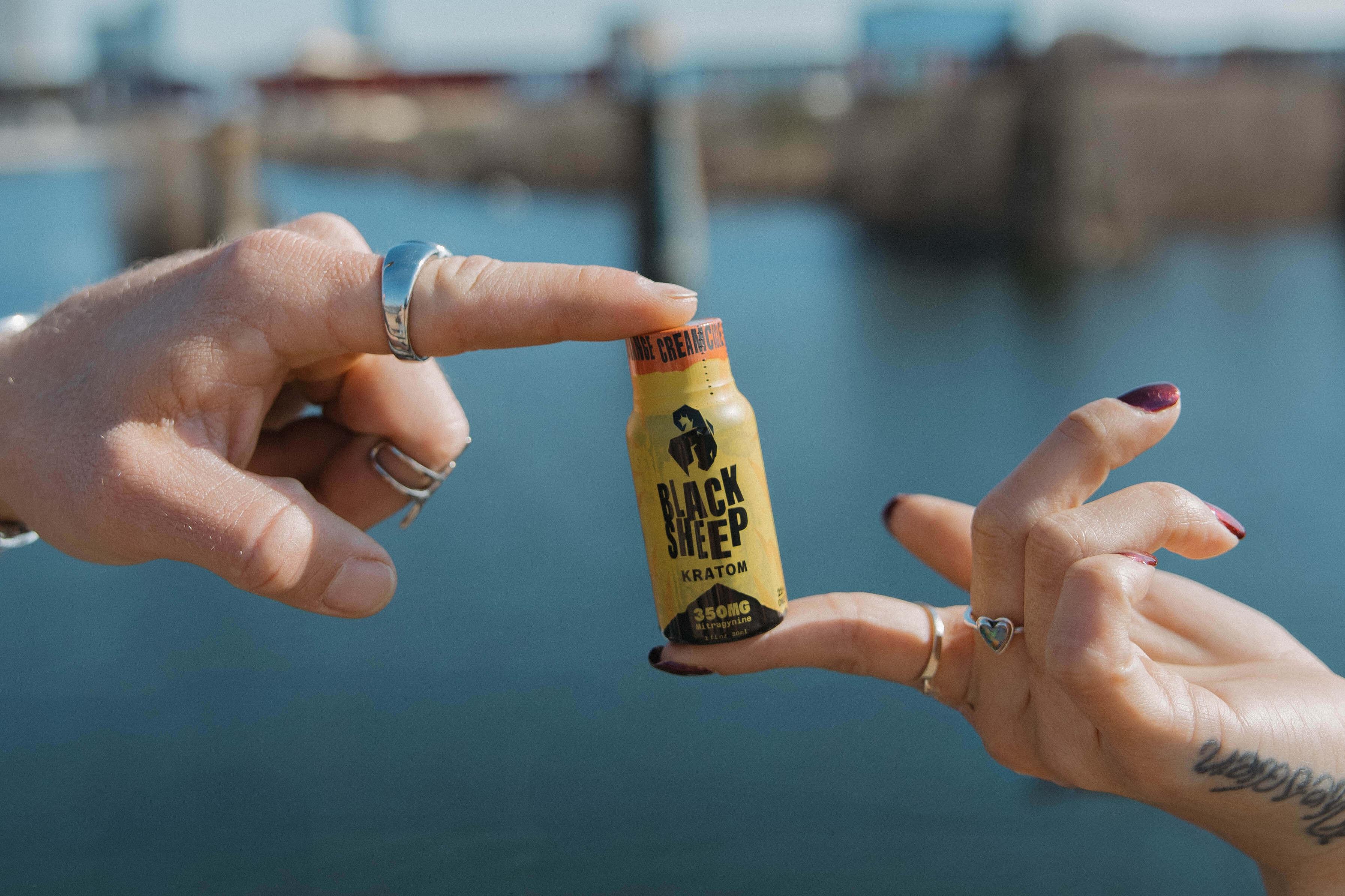 two hands holding kratom shots